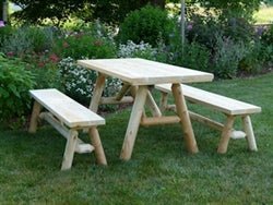 Solid wood farmhouse dining table with sturdy benches, perfect for outdoor gatherings and rustic decor.