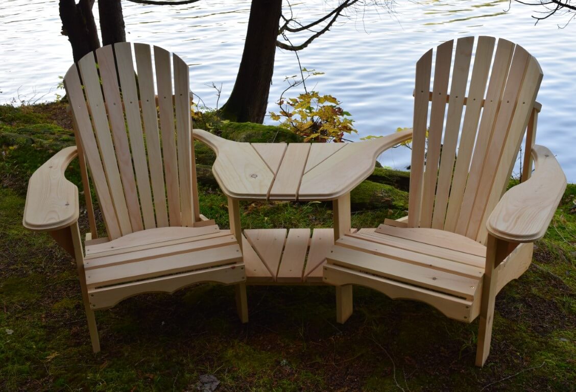  Cedar wood Adirondack chairs with a built-in table, placed near a scenic lake for outdoor relaxation.