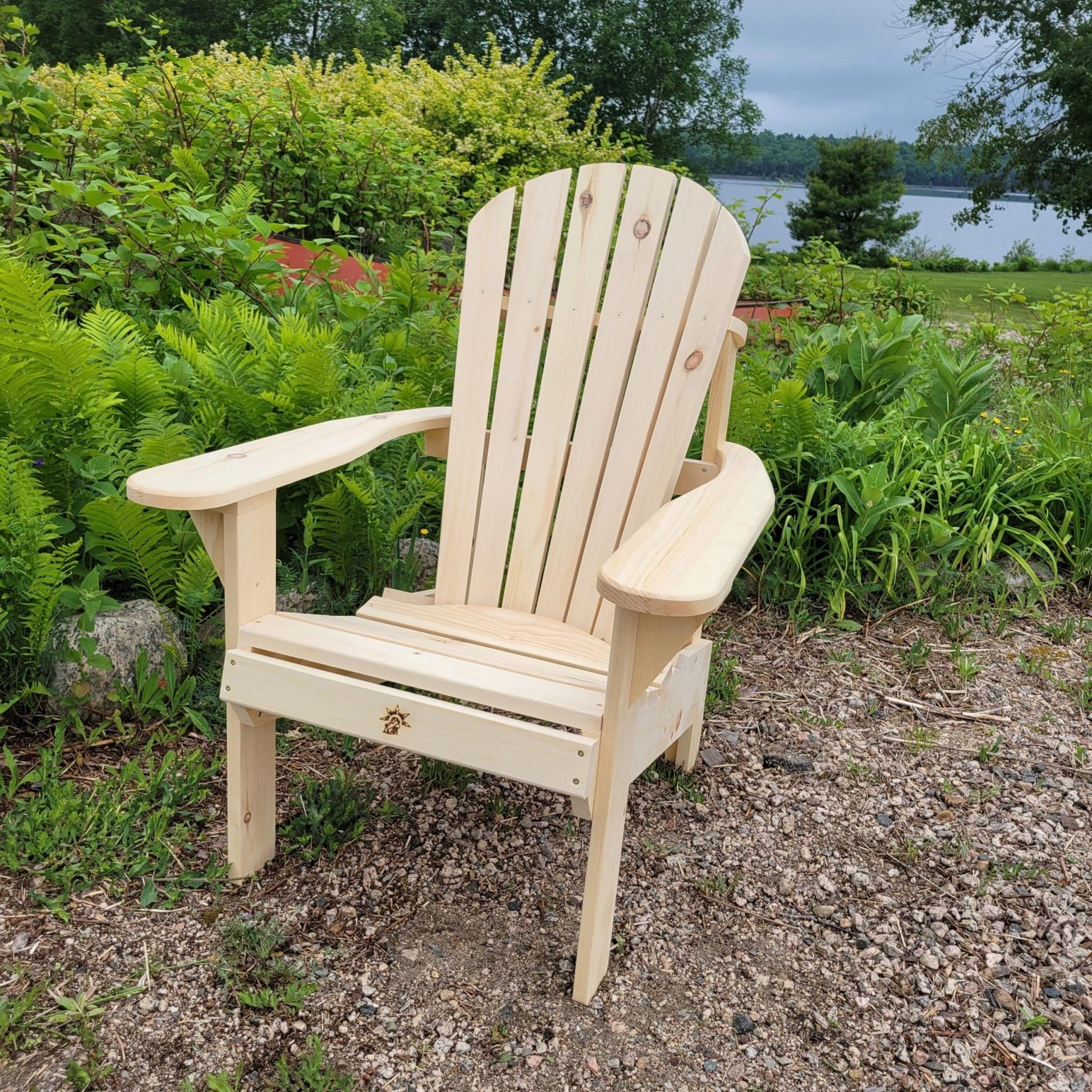 Wooden single patio chair placed outdoors, surrounded by lush greenery and a scenic lake view.